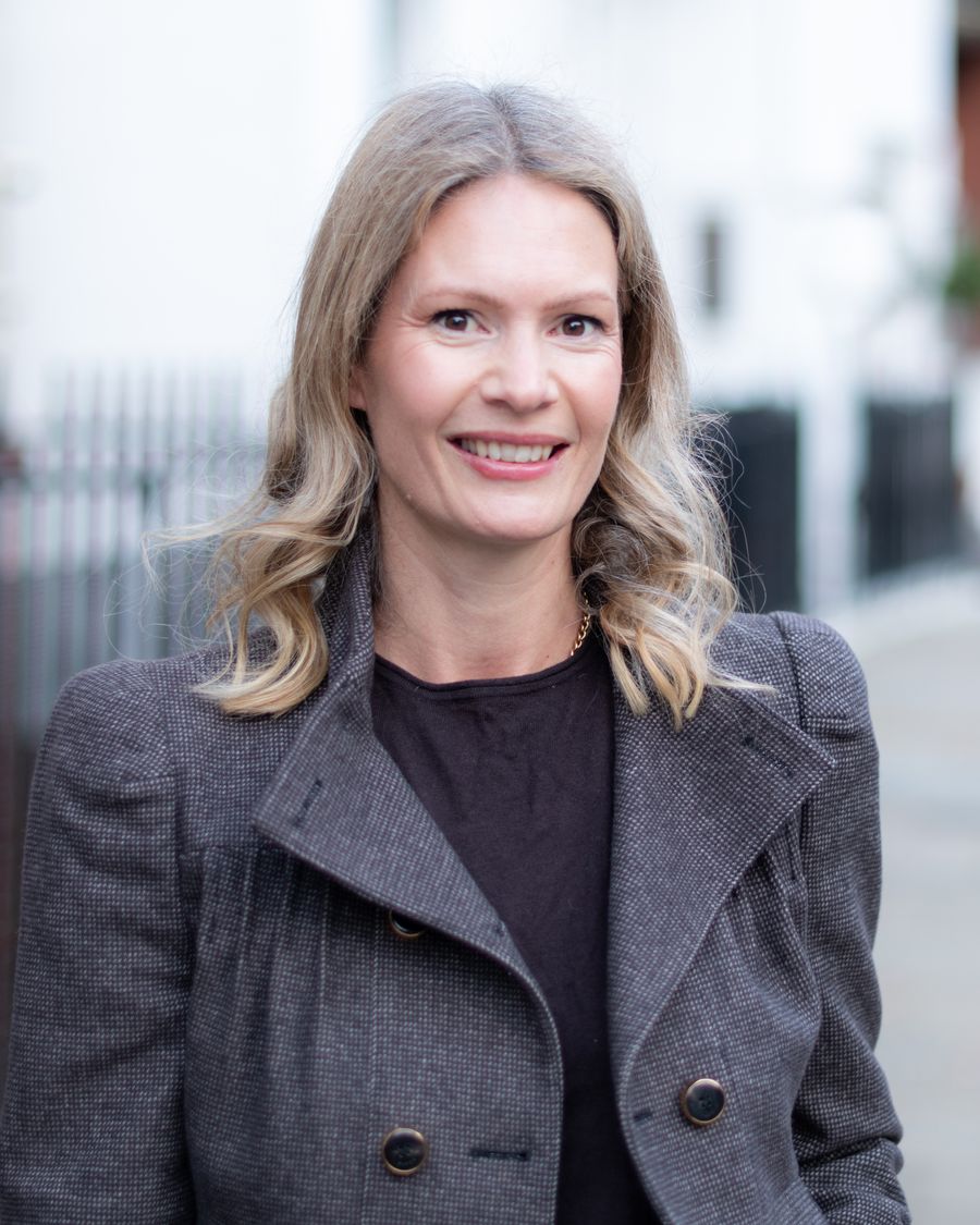 Claudia Nahrath, founder of Goldfinch Consulting, photographed smiling in a Central London street of white stucco and red-brick houses.